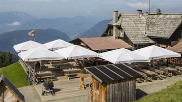 A mountain lodge with outdoor seating and a view of the mountains.