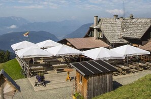 A mountain lodge with outdoor seating and a view of the mountains. - Mobile Home Bodensdorf near Gerlitzen Ski Area (Bodensdorf am Ossiachersee)