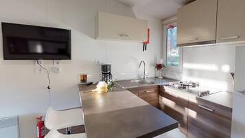 Una cocina moderna con televisión de pantalla plana, cafetera y lavabo.