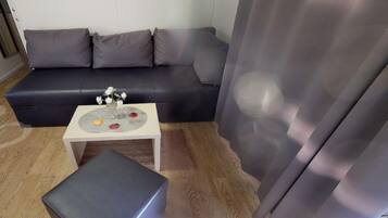 A living room with a dark grey sofa, a small white table with a decorative plate, and a grey ottoman.