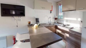 Una cucina moderna con televisore a schermo piatto, macchina del caffè e lavello.