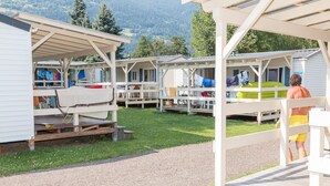 Una fila di case mobili con zone salotto all'aperto, ciascuna dotata di un portico coperto e vista sul paesaggio circostante.