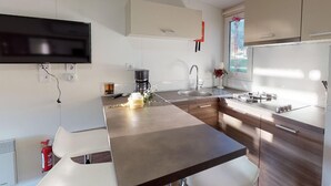 A modern kitchen with a flat-screen TV, a coffee machine, and a sink.