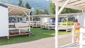 A row of mobile homes with outdoor seating areas and a view of the mountains in the background.