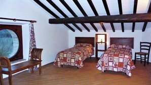 Een kamer met twee bedden, houten meubels, een groot raam en een betegelde vloer.