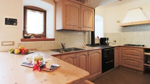 Una cocina con armarios de madera, un fregadero, una estufa y una ventana con persianas.