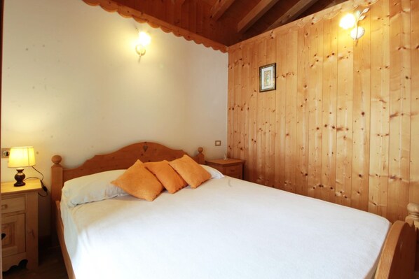 A wooden-paneled bedroom with a bed, nightstands, and wall-mounted lights.