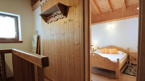 Una habitación de madera con cama, mesita de noche, ventana y techo de madera.
