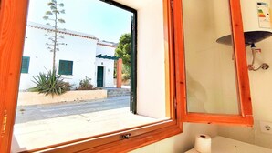 Ein Badezimmer mit Fenster, Spiegel und Papierrolle.