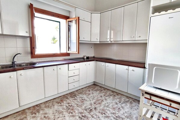 A kitchen with white cabinets, a wooden countertop, and a window.
