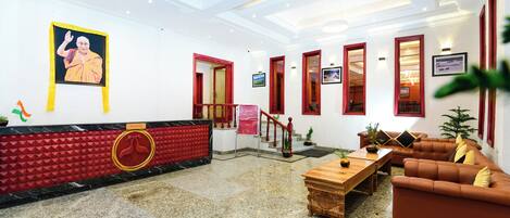 A hotel lobby with a reception desk, seating area, and a staircase.