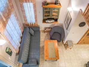 Una sala de estar con un sofá, una silla, una mesa de madera, un aparador y un reloj en la pared.