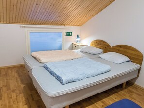 En enkelt seng med trægavl, senget lampe og et vindue med persienner.