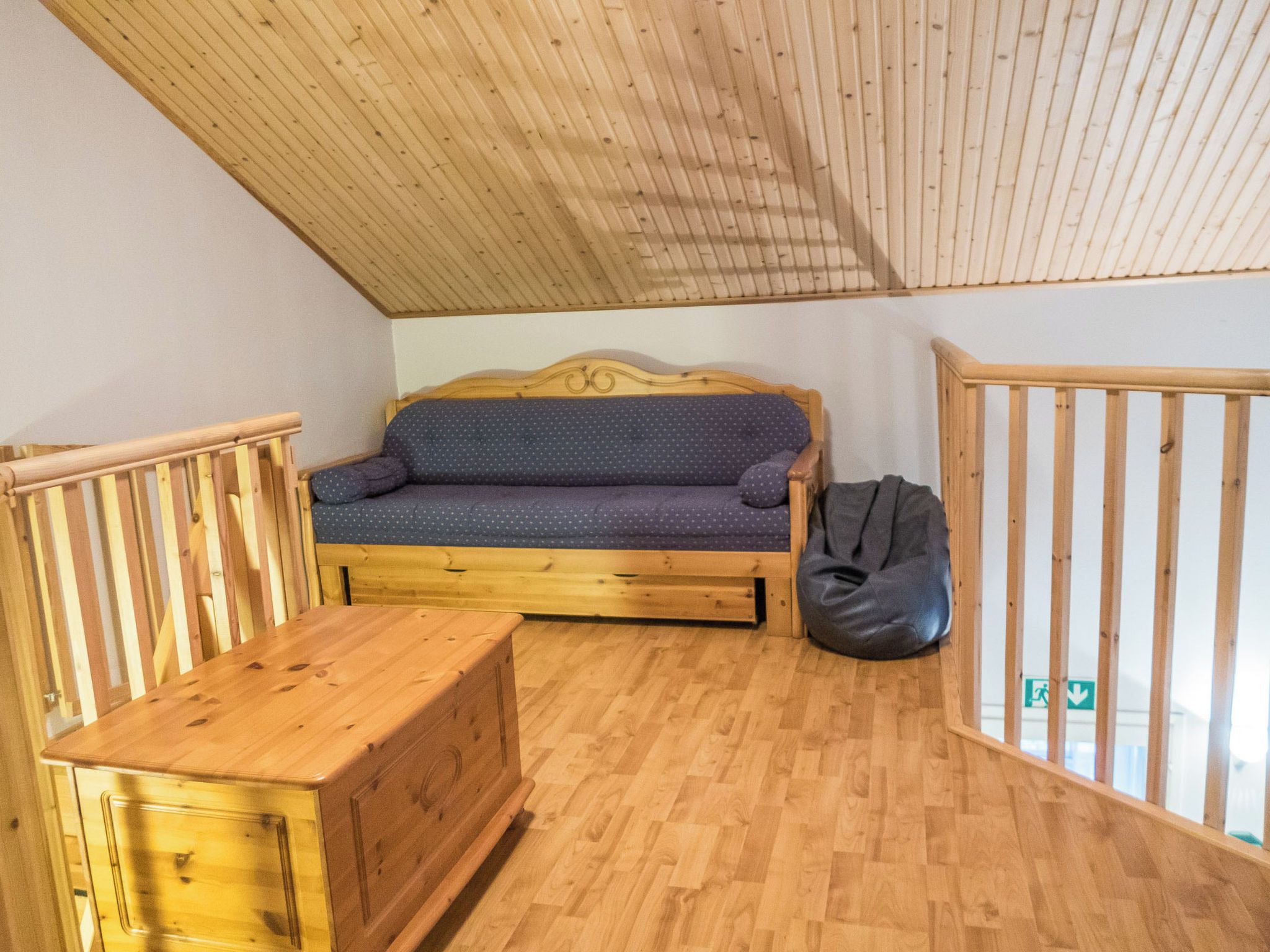 Une chambre à coucher aménagée dans les combles, avec un canapé, une commode en bois et un fauteuil poire.