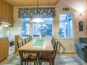 A dining area with a wooden table, chairs, and a window with a view of trees. - Öjkatti by Interhome (Sotkamo)