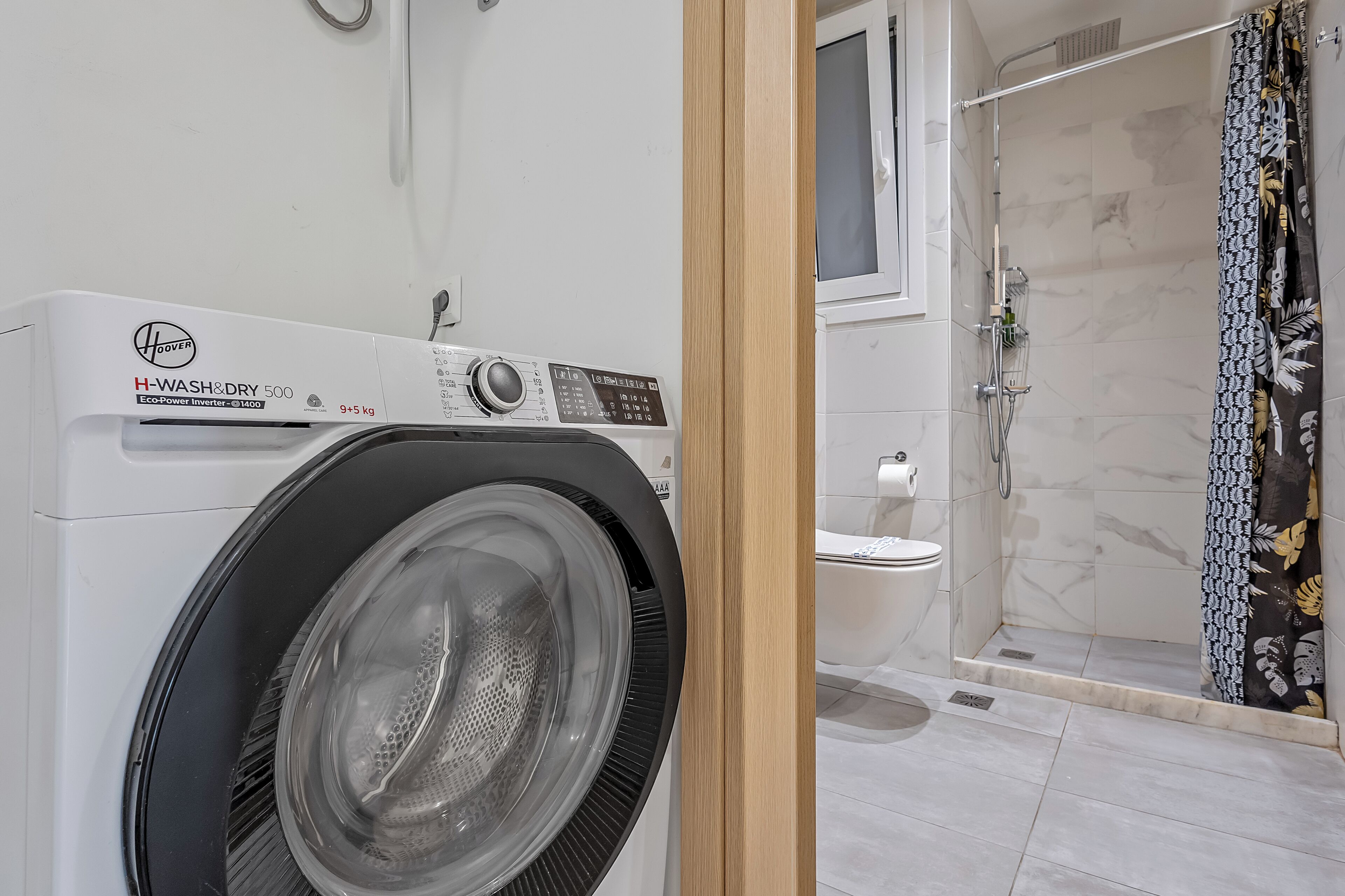 A modern bathroom with a H-WASH&DRY 500 washer, a toilet, and a shower area.