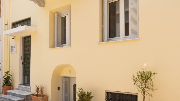 A yellow building with a door, windows, and potted plants. - Athens Plaka Family Suites (Athens)