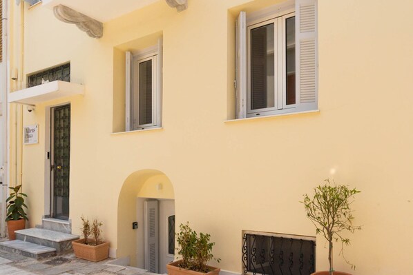 A yellow building with a door, windows, and potted plants. - Athens Plaka Family Suites (Athens)
