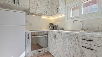 Una cocina compacta con horno empotrado, cafetera y ventana sobre el fregadero.