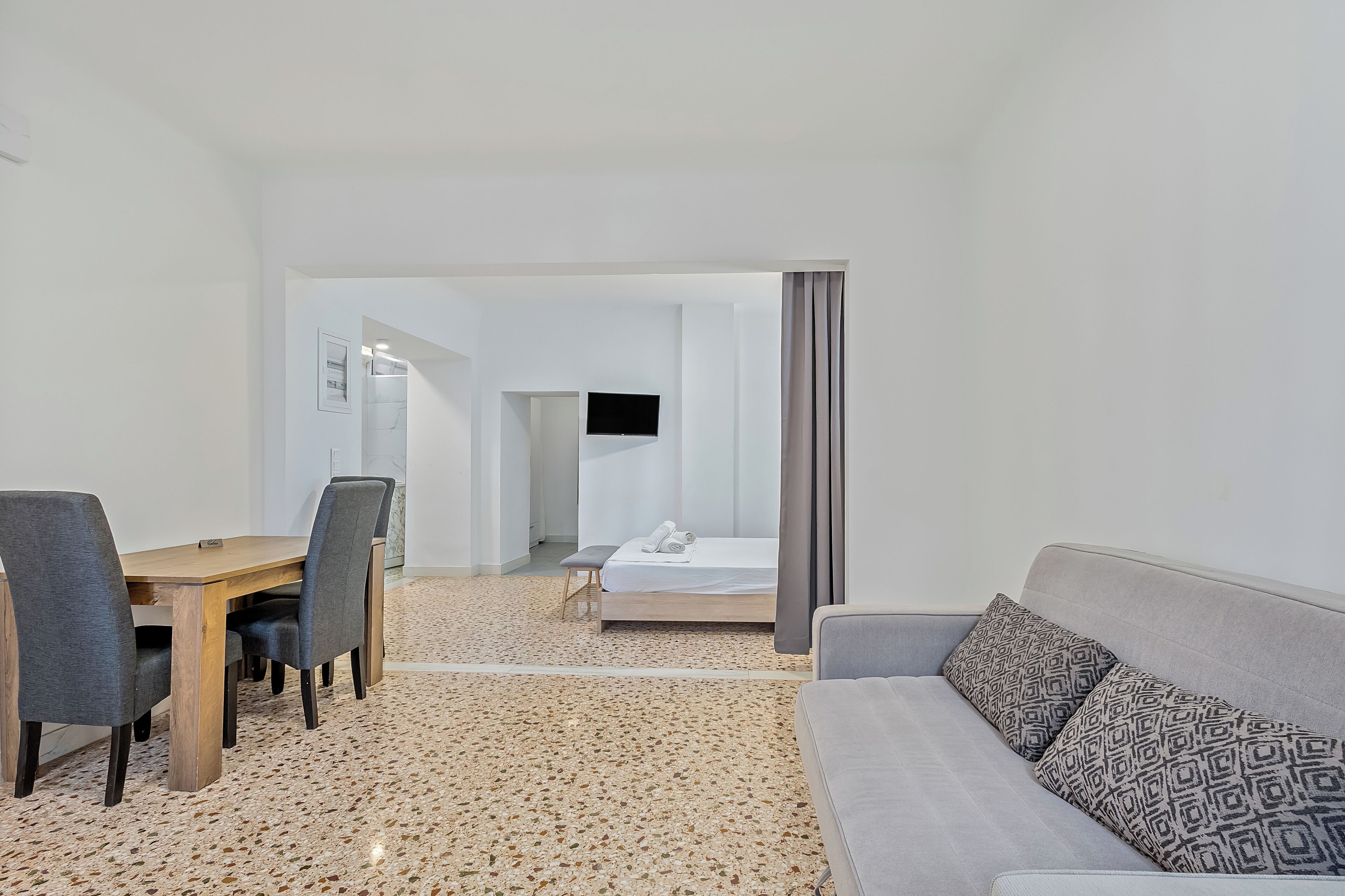 Una habitación de hotel moderna con comedor, sofá y cama.