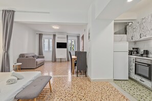A modern hotel room with a kitchenette, a sofa, a dining table, and a bench. - Athens Plaka Family Suites (Athens)