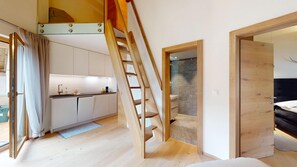 A modern interior with a kitchen, a staircase, and a bedroom. - Beautiful, stylishly furnished 2-room flat on the 2nd floor with gallery, 60 m2, (Sils/Segl Maria)