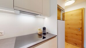 A kitchen with a stainless steel countertop, a coffee maker, and a wooden cabinet. - Beautiful, stylishly furnished 2-room flat on the 2nd floor with gallery, 60 m2, (Sils/Segl Maria)