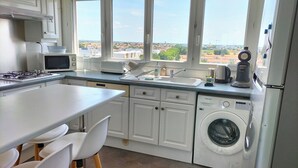 Una cucina moderna con lavatrice e asciugatrice integrate, mobili bianchi e un'ampia finestra con vista sulla città.