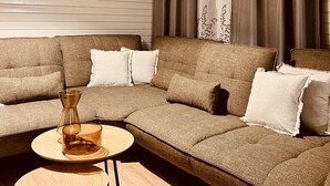 Un salon moderne avec un canapé d’angle, une petite table ronde et une suspension.