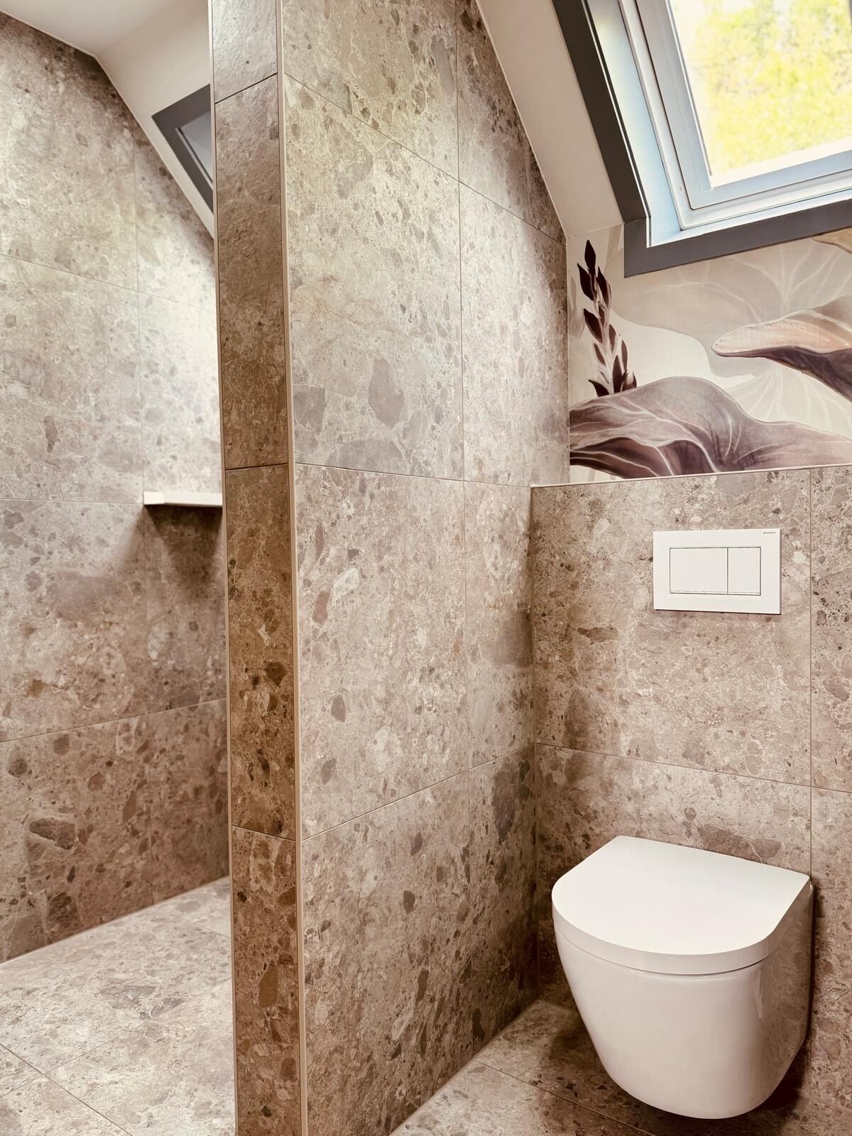 A modern bathroom with a toilet, a shower area, and a window providing natural light.
