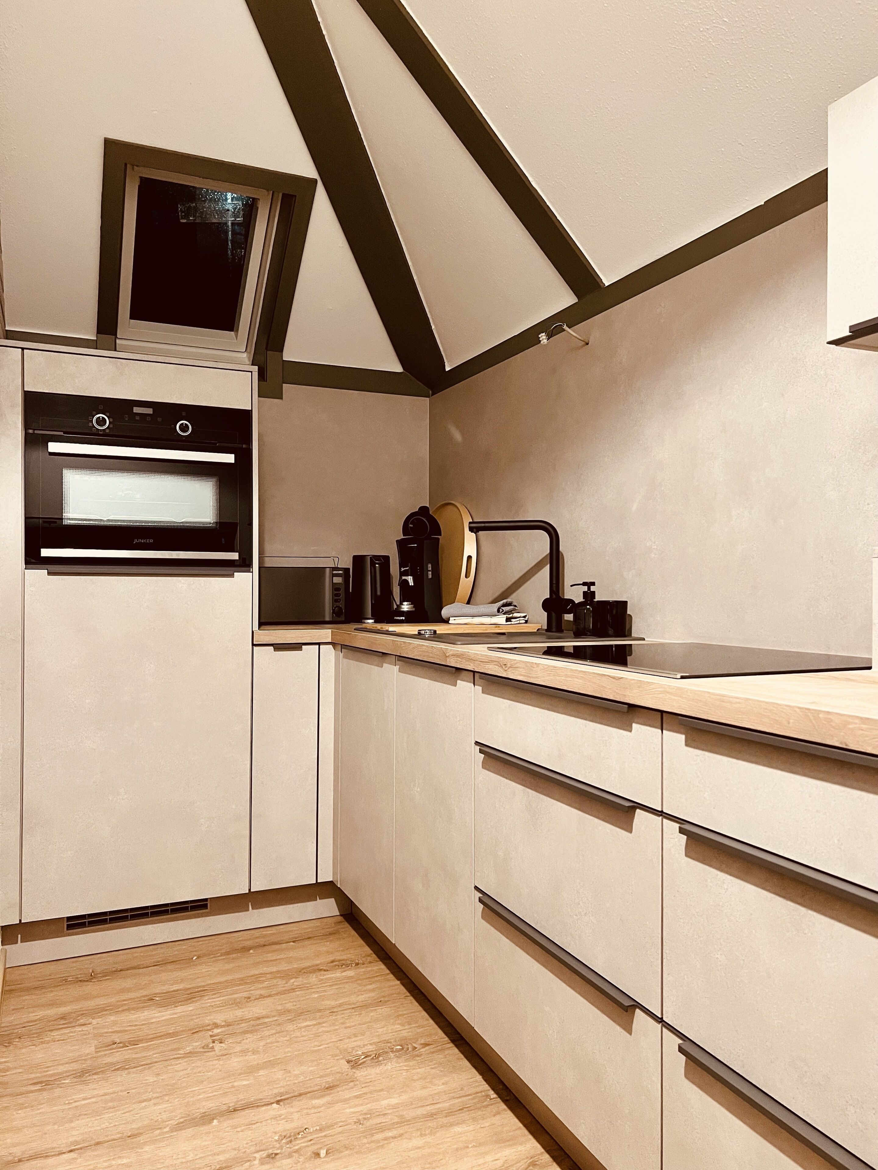 Eine moderne Küche mit Holzschränken, einem eingebauten Backofen und einer Kaffeemaschine.