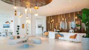 A modern reception area with a marble counter, wooden panel wall, and contemporary lighting fixtures. - Mina Hotel and Residences By the Torch (Doha)