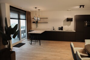 Moderni keittiö, jossa on marmoritaso, mustat kaapit ja suuri ikkuna, jossa on sälekaihtimet.