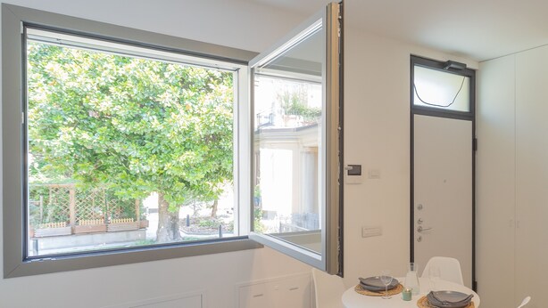 A room with a window, a table with chairs, and a door. - Salvia Ginepro Apartments (Como)