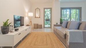 A modern living room with a flat-screen TV, a lamp, a sofa, and a large window. - Salvia Ginepro Apartments (Como)