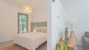 A bedroom with a bed, a window, a lamp, and a small table with a plant. - Salvia Ginepro Apartments (Como)