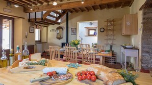 A rustic dining area with wooden furniture, a variety of food items on the table, and a stone wall. - Casale Mollina 6 2 (Anghiari)
