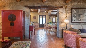 A rustic interior with exposed stone walls, a wooden dining table set for four, and a red cabinet. - Casale Mollina 6 2 (Anghiari)