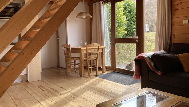 Un interior de madera con comedor, una mesa de vidrio y un sofá.