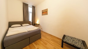 Una camera da letto con un letto, un comodino, una lampada e una panca.