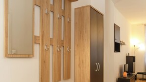 Una camera moderna con un armadio in legno, uno specchio, un piccolo mobile e una televisione.