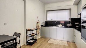 Eine kompakte Küche mit weißen Schränken, einer schwarzen Arbeitsplatte und einem eingebauten Backofen.