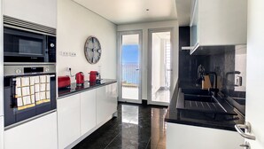 Une cuisine moderne avec des meubles blancs, un four à micro-ondes de marque Bosch, une machine à café rouge et une horloge murale.