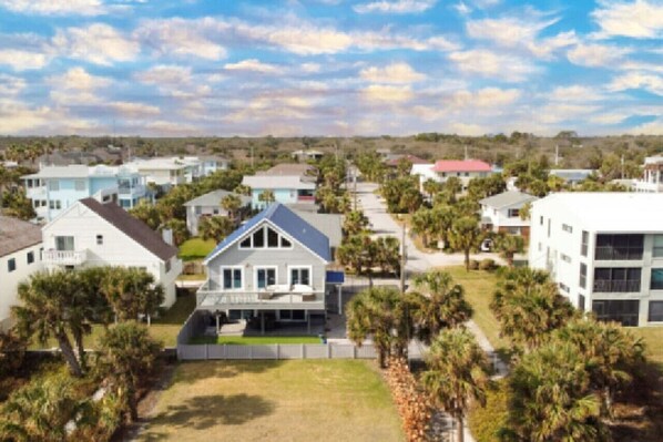 A residential area with houses, including a two-story house with a blue roof and a white building with a red roof. - A Shore Thing: Holidays by the Beach! (St. Augustine Beach)