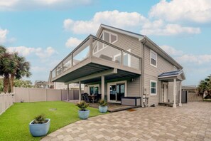 A modern two-story house with a covered patio, a fenced backyard, and a well-maintained lawn. - A Shore Thing: Holidays by the Beach! (St. Augustine Beach)