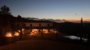 A large house with a covered patio area, a swimming pool, and a view of the surrounding landscape.