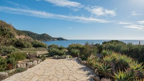 Un sendero de piedra que lleva a una zona costera con exuberante vegetación y vistas al mar.