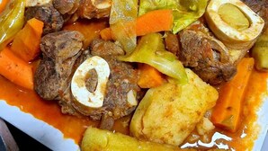 A dish with meat, potatoes, and vegetables in a sauce.