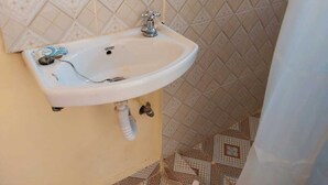 A bathroom with a white sink mounted on a beige wall, a patterned tile backsplash, and a patterned floor.