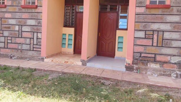 A building with a pink facade, a wooden door, and a small porch area.